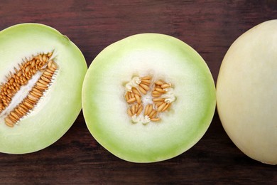 Cut and whole tasty ripe melons on wooden table, flat lay