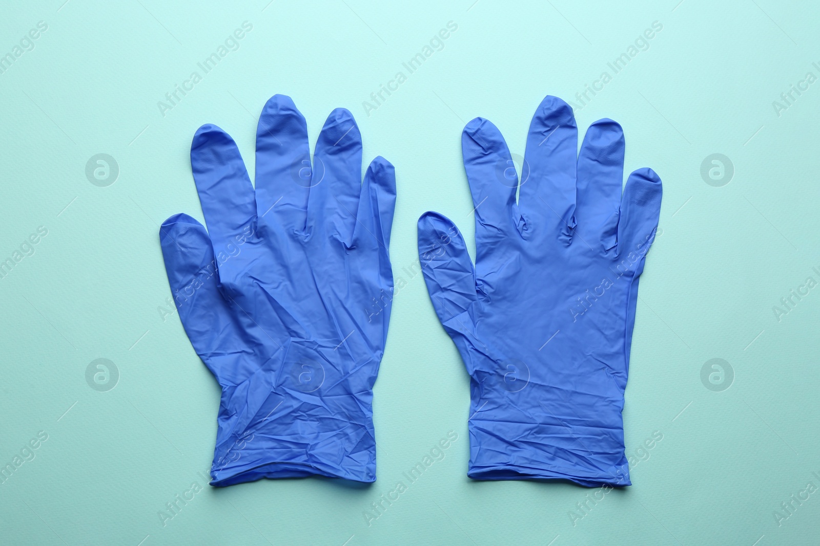 Photo of Pair of medical gloves on light blue background, flat lay