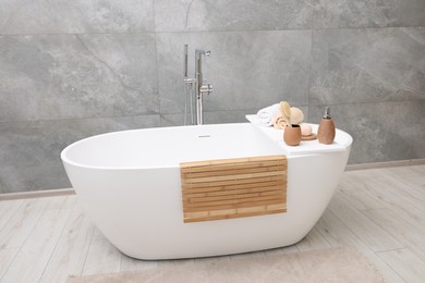 Photo of Different personal care products and accessories on bath tub in bathroom