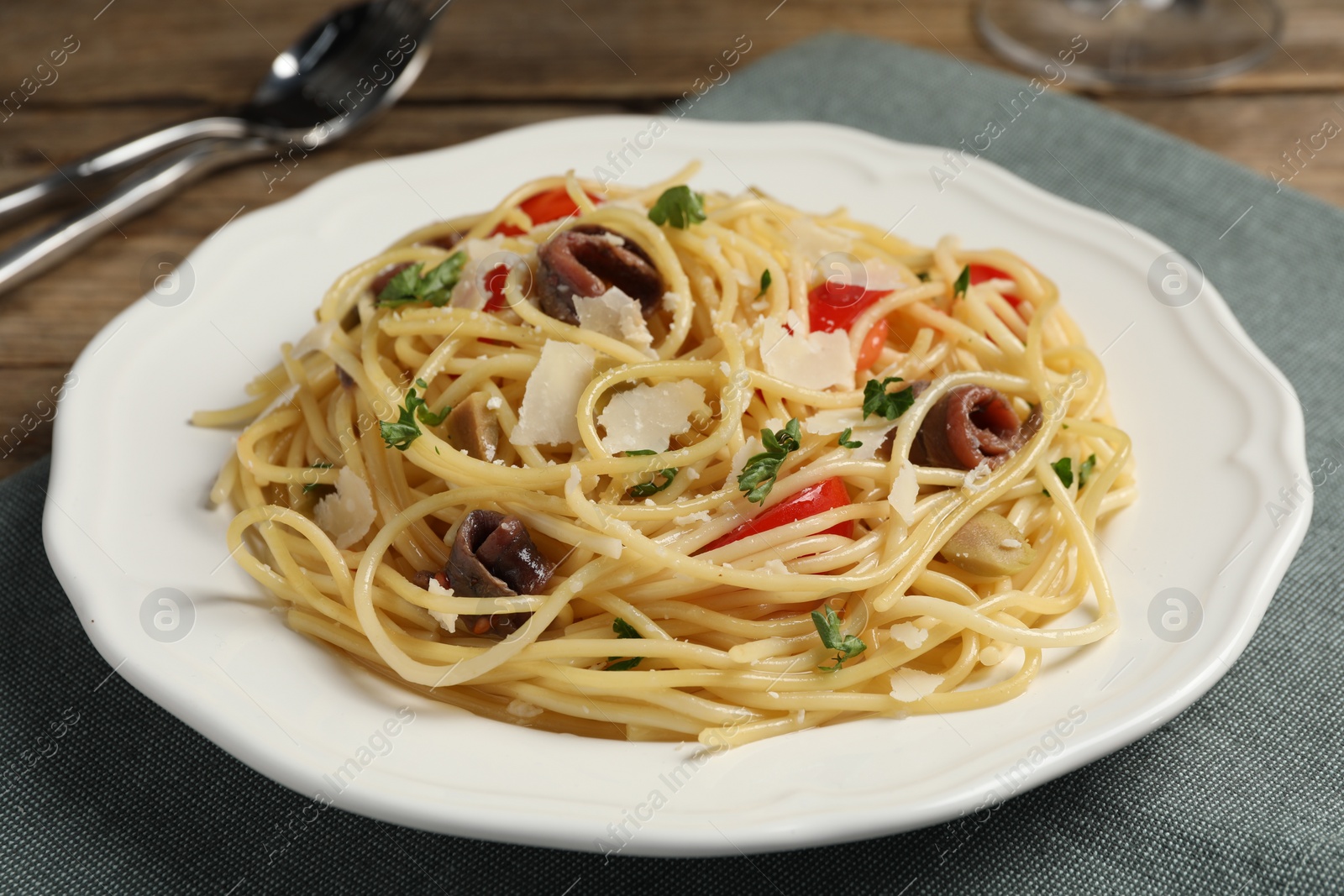 Photo of Delicious pasta with anchovies, tomatoes and parmesan cheese on table, closeup