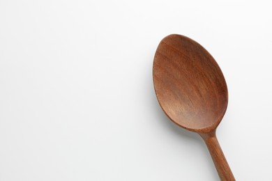 Photo of One wooden spoon on white background, top view. Space for text