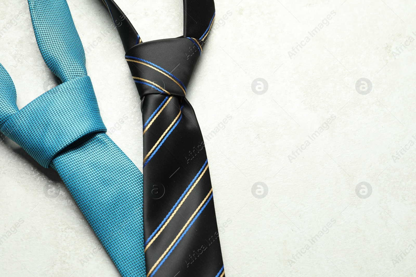 Photo of Two neckties on light textured table, above view. Space for text