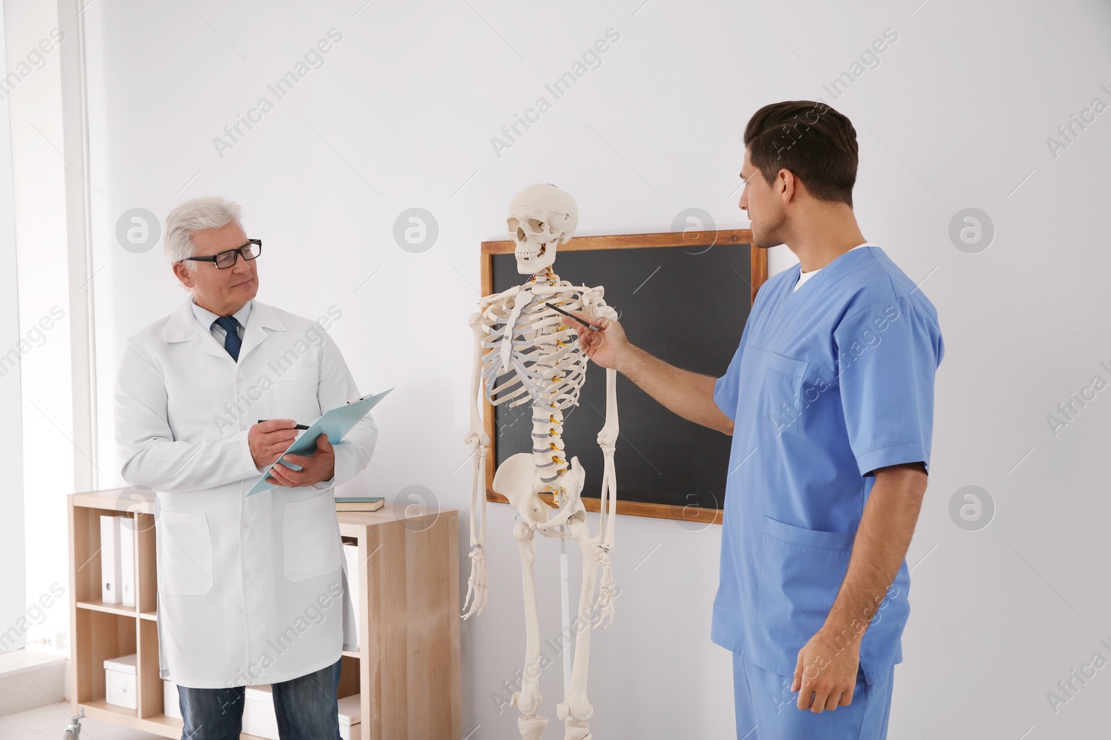 Photo of Medical student and professor studying human skeleton anatomy in classroom