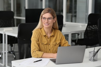Woman working on laptop at white desk in office