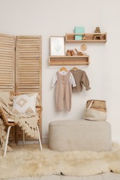 Photo of Children's room interior with stylish wooden furniture, baby clothes and decor elements