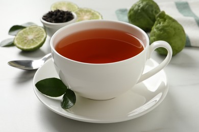 Photo of Cup of tasty bergamot tea on white table, closeup