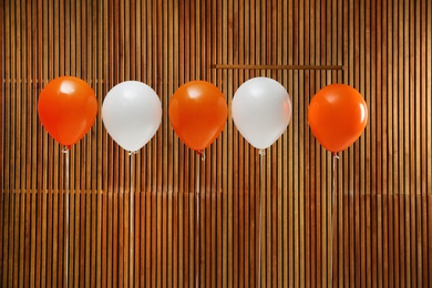 Photo of Colorful balloons against wooden wall. Halloween party