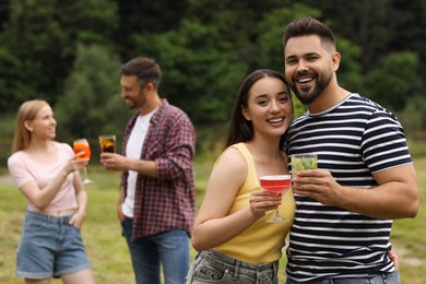 Photo of Friends having cocktail party outdoors. Happy couple with glasses of drinks, selective focus