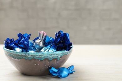 Candies in colorful wrappers on white wooden table