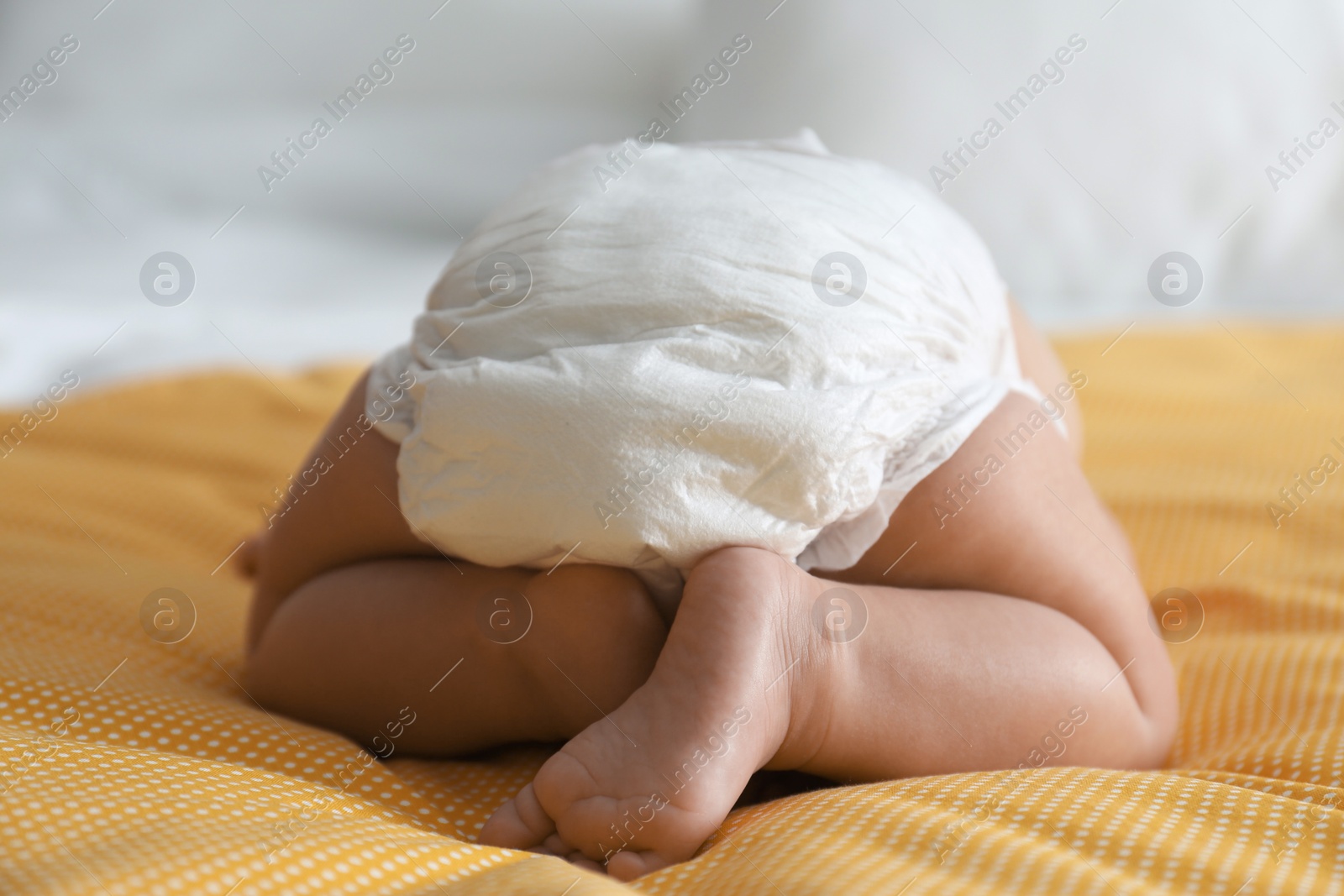 Photo of Cute little baby in diaper on yellow blanket