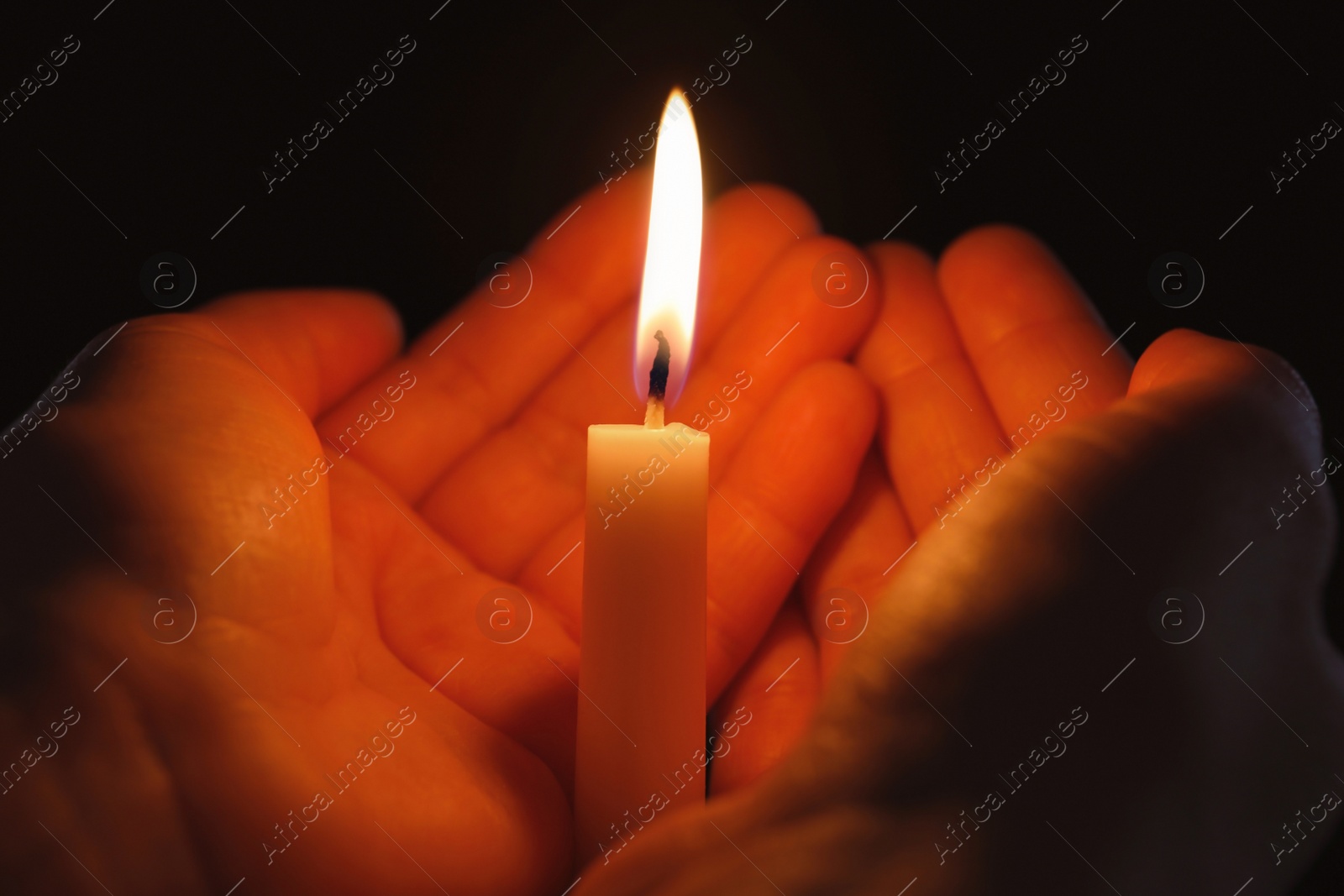 Photo of Young person holding burning candle in darkness, closeup