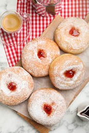 Photo of Delicious jam donuts served with coffee on white marble table, flat lay