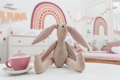 Toy bunny and cup on white table in child's bedroom. Montessori interior