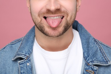 Photo of Man showing his tongue on pink background, closeup