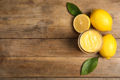 Delicious lemon curd and fresh fruits on wooden table, flat lay. Space for text