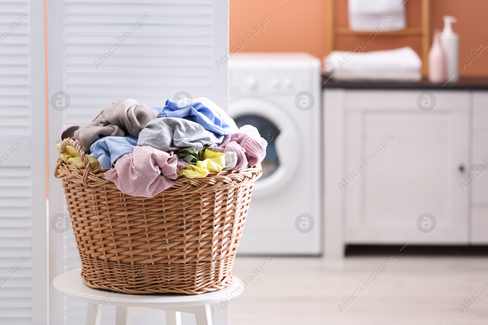 Photo of Wicker basket with dirty laundry indoors, space for text