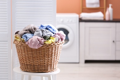 Wicker basket with dirty laundry indoors, space for text