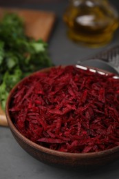 Photo of Grated red beet in bowl on table, closeup