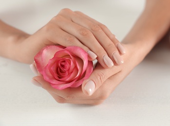 Woman holding flower at table, closeup. Spa treatment