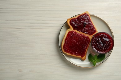 Photo of Delicious toasts served with jam and mint on white wooden table, top view. Space for text