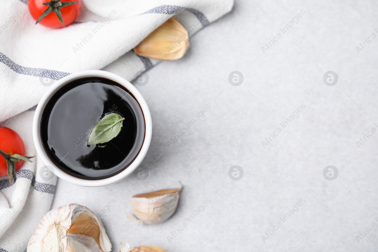 Photo of Organic balsamic vinegar and cooking ingredients on white table, flat lay. Space for text