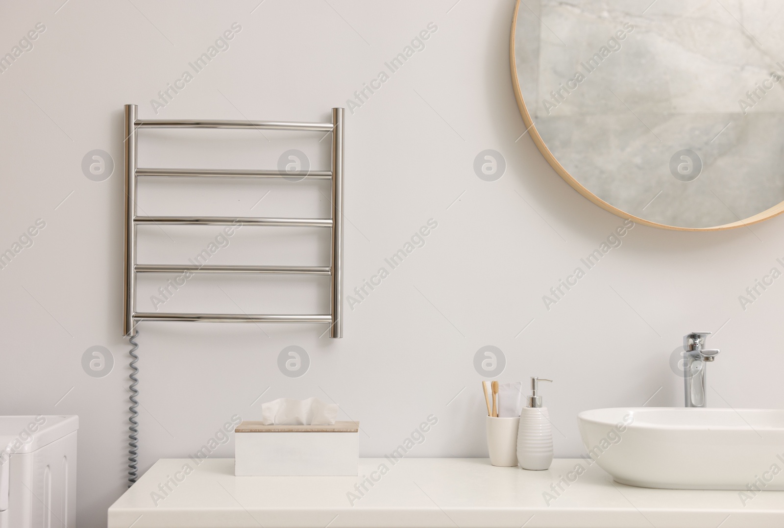 Photo of Heated towel rail on white wall in bathroom