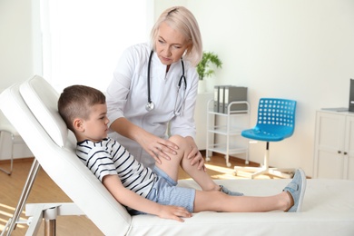 Doctor examining little patient with knee problem in clinic