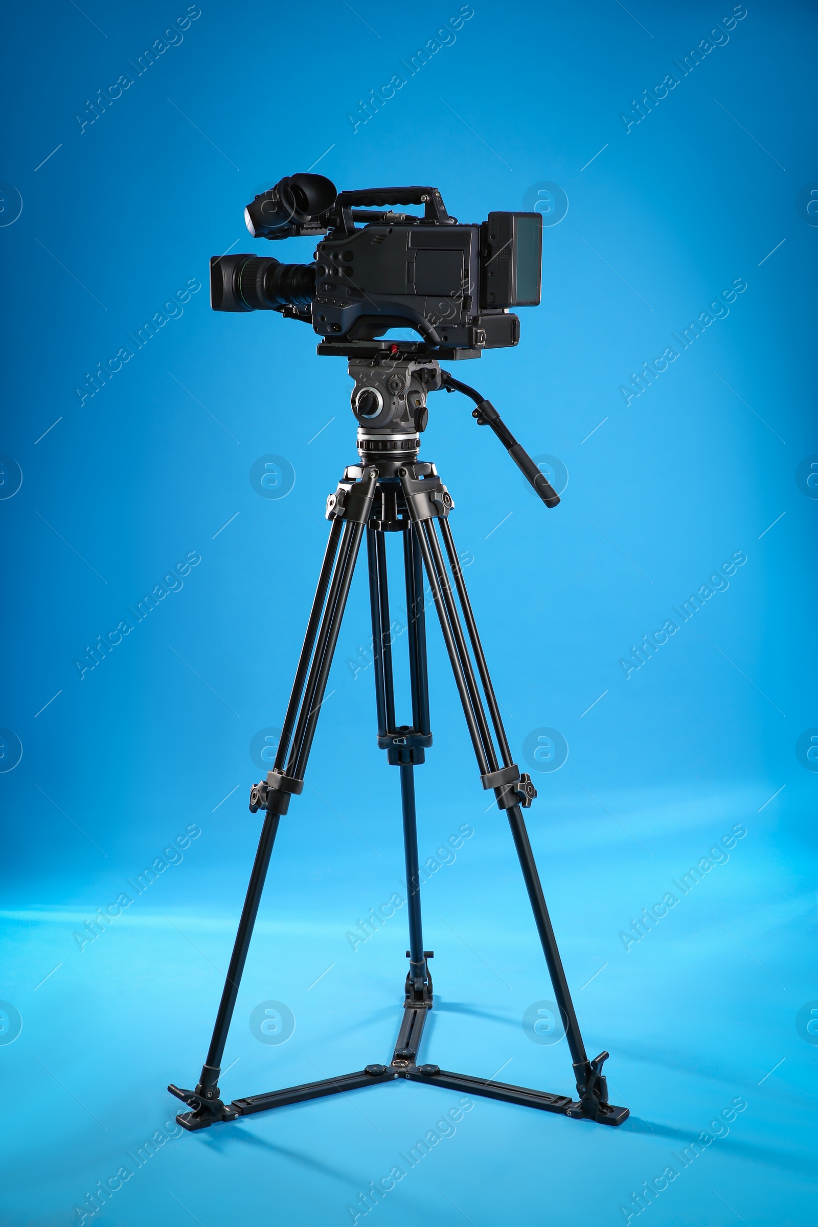 Photo of Modern professional video camera on blue background