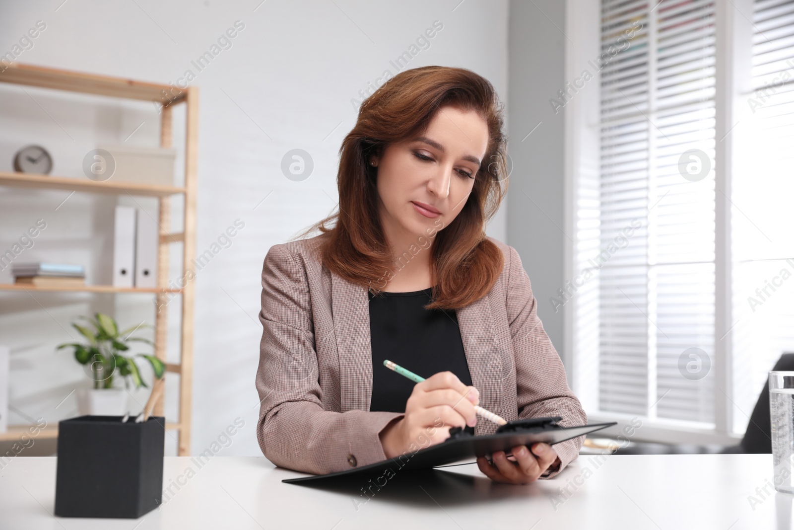 Photo of Portrait of psychotherapist with clipboard at table in office