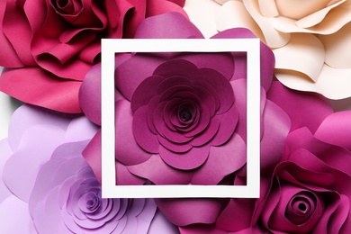 Different beautiful flowers made of paper and frame as background, top view