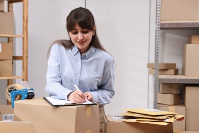 Parcel packing. Post office worker with clipboard writing notes indoors