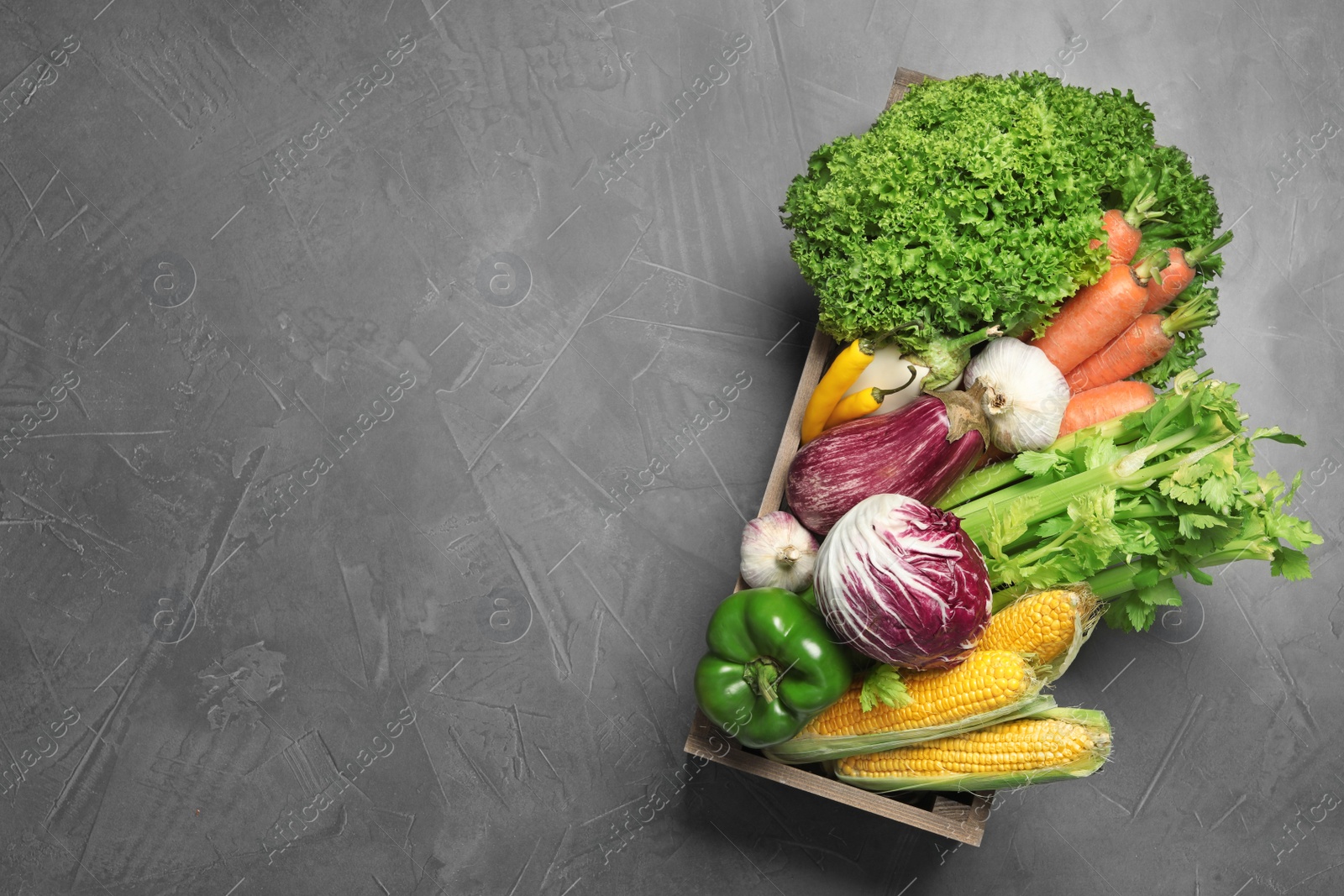 Photo of Crate with fresh vegetables on grey table, top view. Space for text