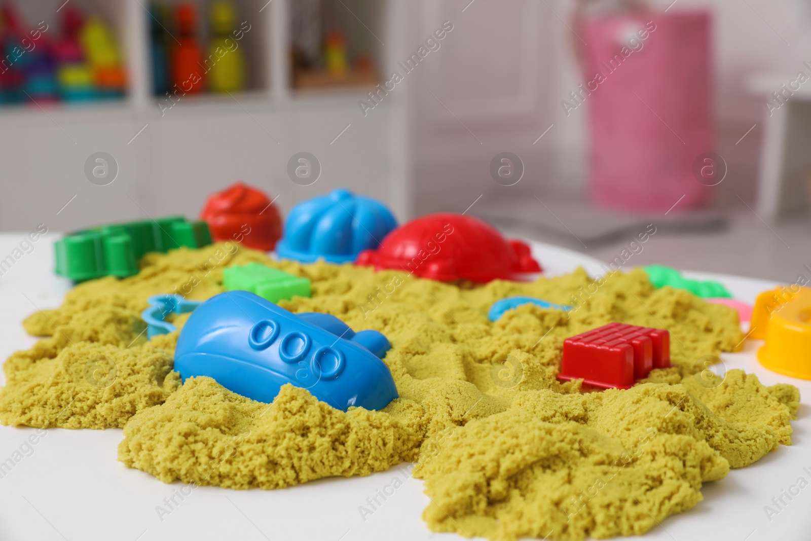 Photo of Bright kinetic sand and toys on white table indoors