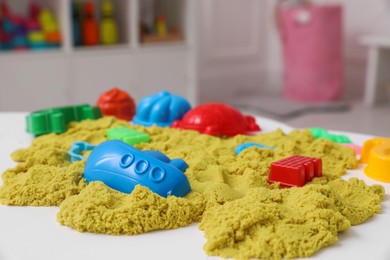 Bright kinetic sand and toys on white table indoors