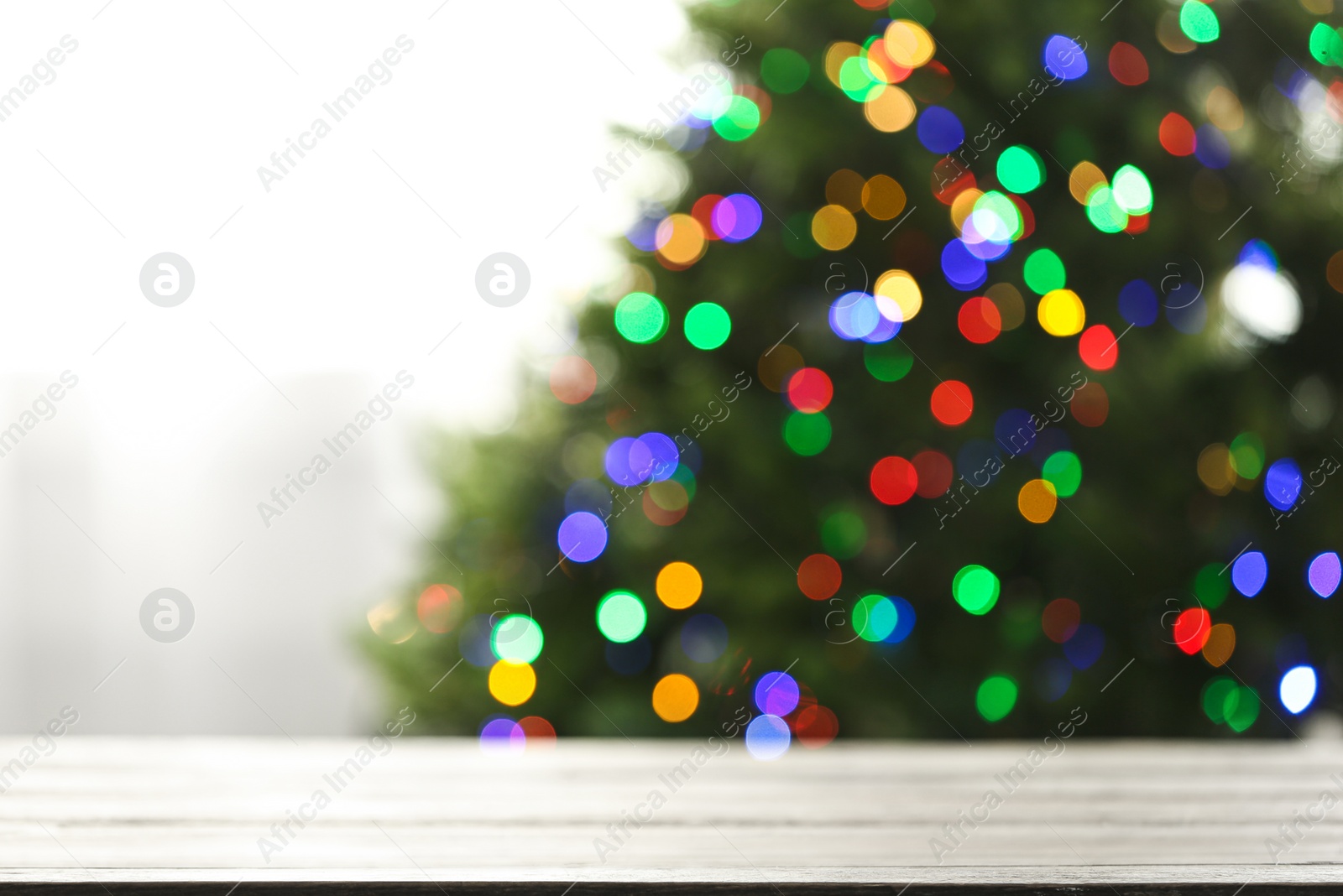 Photo of Empty table and blurred fir tree with colorful Christmas lights on background, bokeh effect. Space for design