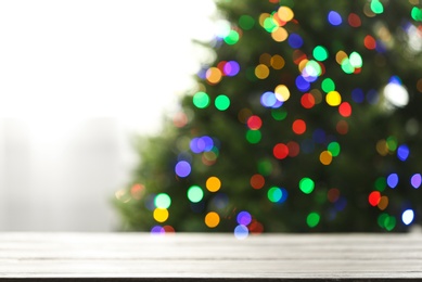 Photo of Empty table and blurred fir tree with colorful Christmas lights on background, bokeh effect. Space for design