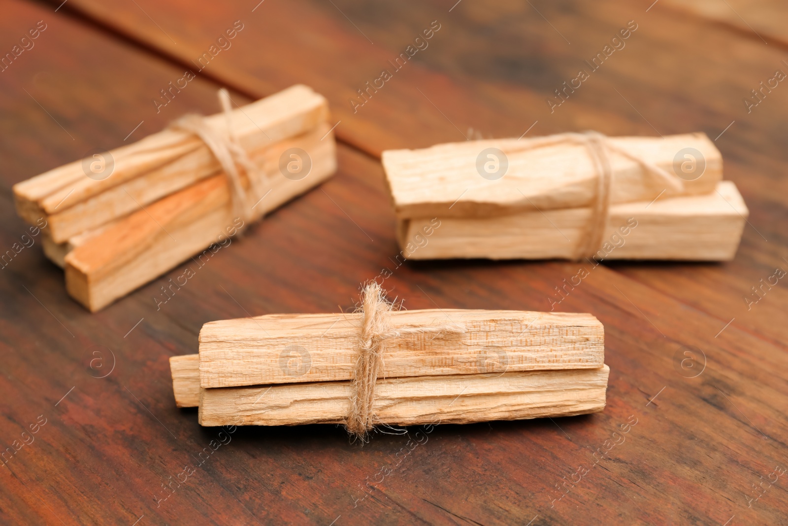 Photo of Bunches of tied Palo Santo sticks on wooden table, closeup