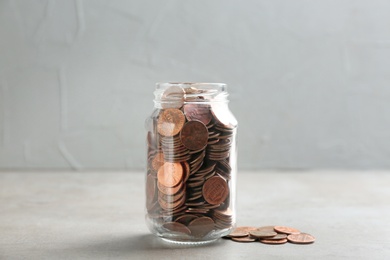 Photo of Glass jar and coins on table against grey background