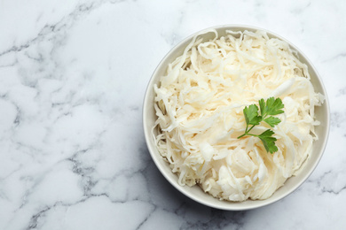 Tasty fermented cabbage with parsley on white marble table, top view. Space for text