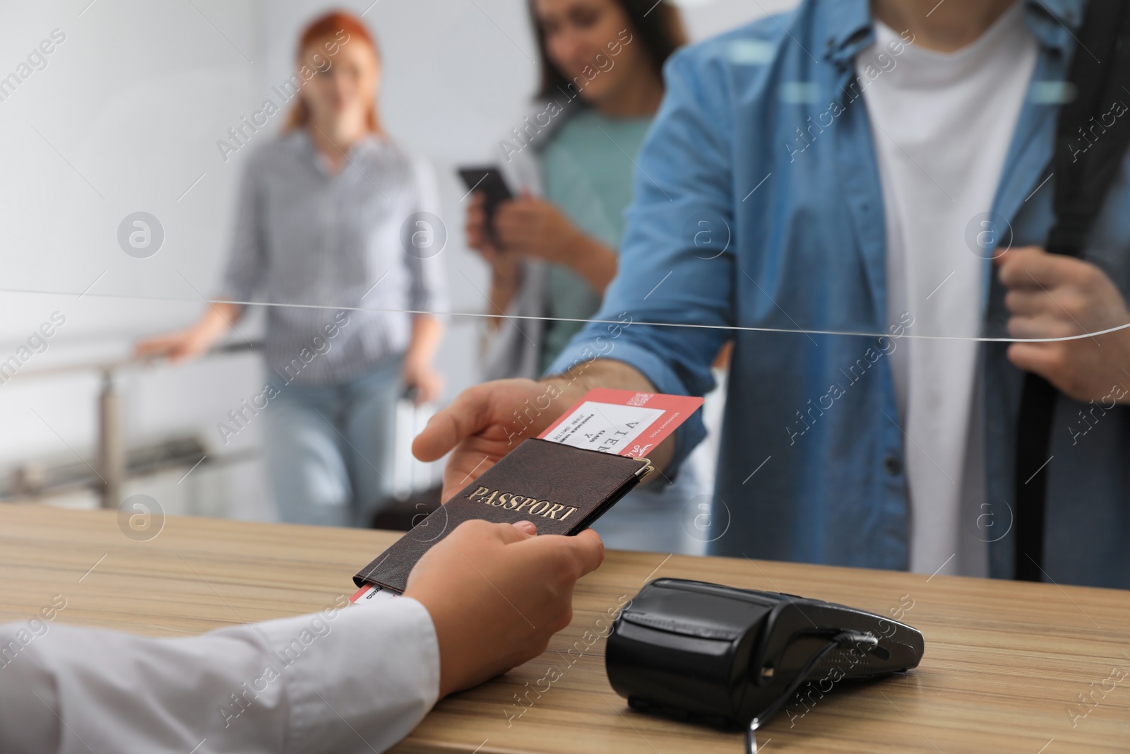 Photo of Agent giving passport with ticket to client at check-in desk in airport, closeup