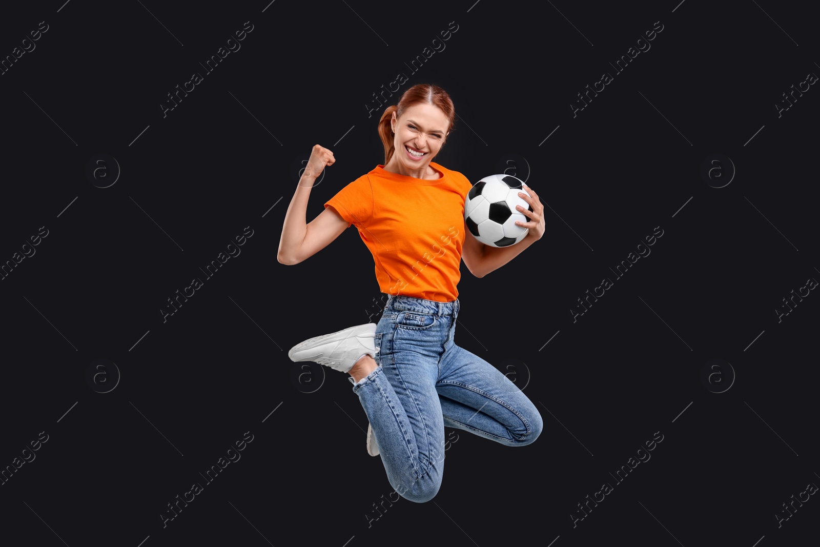 Photo of Happy fan with football ball jumping on black background