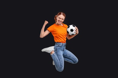 Photo of Happy fan with football ball jumping on black background