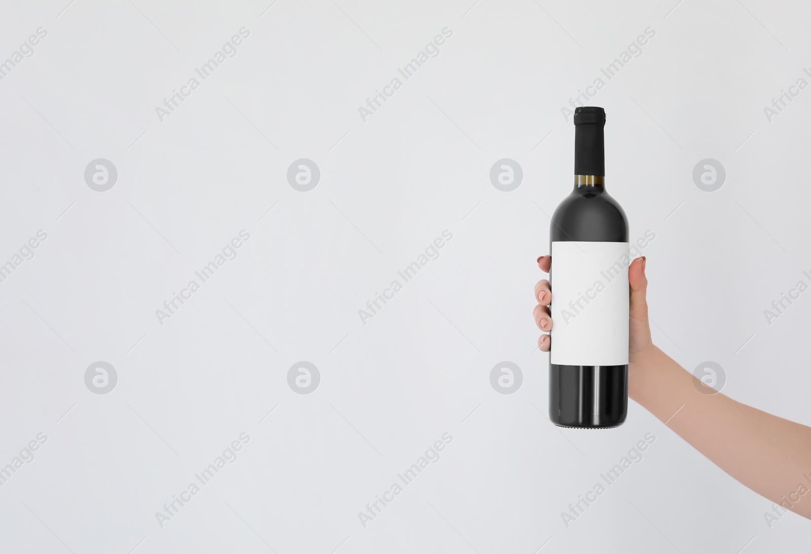 Photo of Woman holding bottle of wine on light background