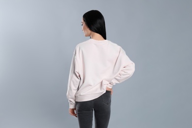 Young woman in sweater on grey background. Mock up for design