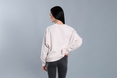 Photo of Young woman in sweater on grey background. Mock up for design