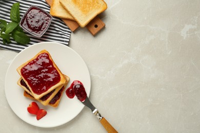 Photo of Toasts served with tasty jam, mint and strawberry on light marble table, flat lay. Space for text