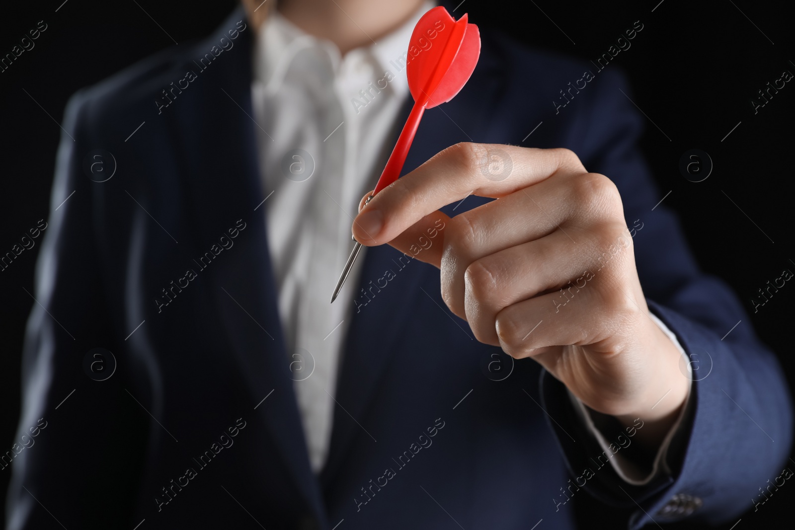 Photo of Businesswoman holding red dart on black background, closeup