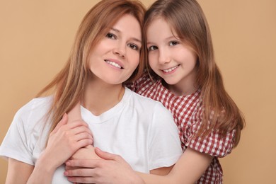 Photo of Portrait of happy mother and her cute daughter on beige background