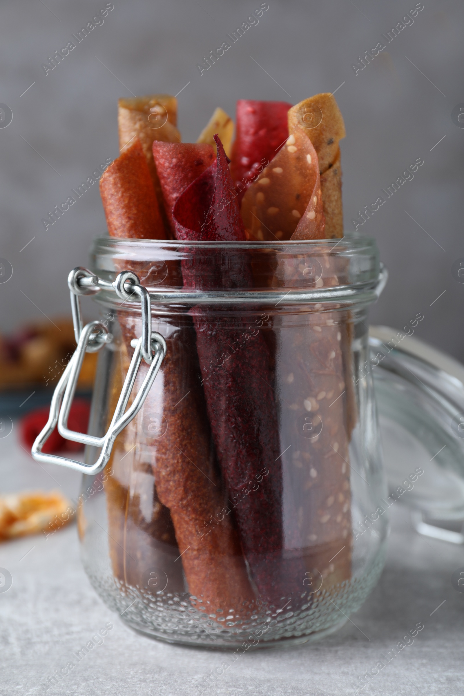 Photo of Delicious fruit leather rolls on grey table