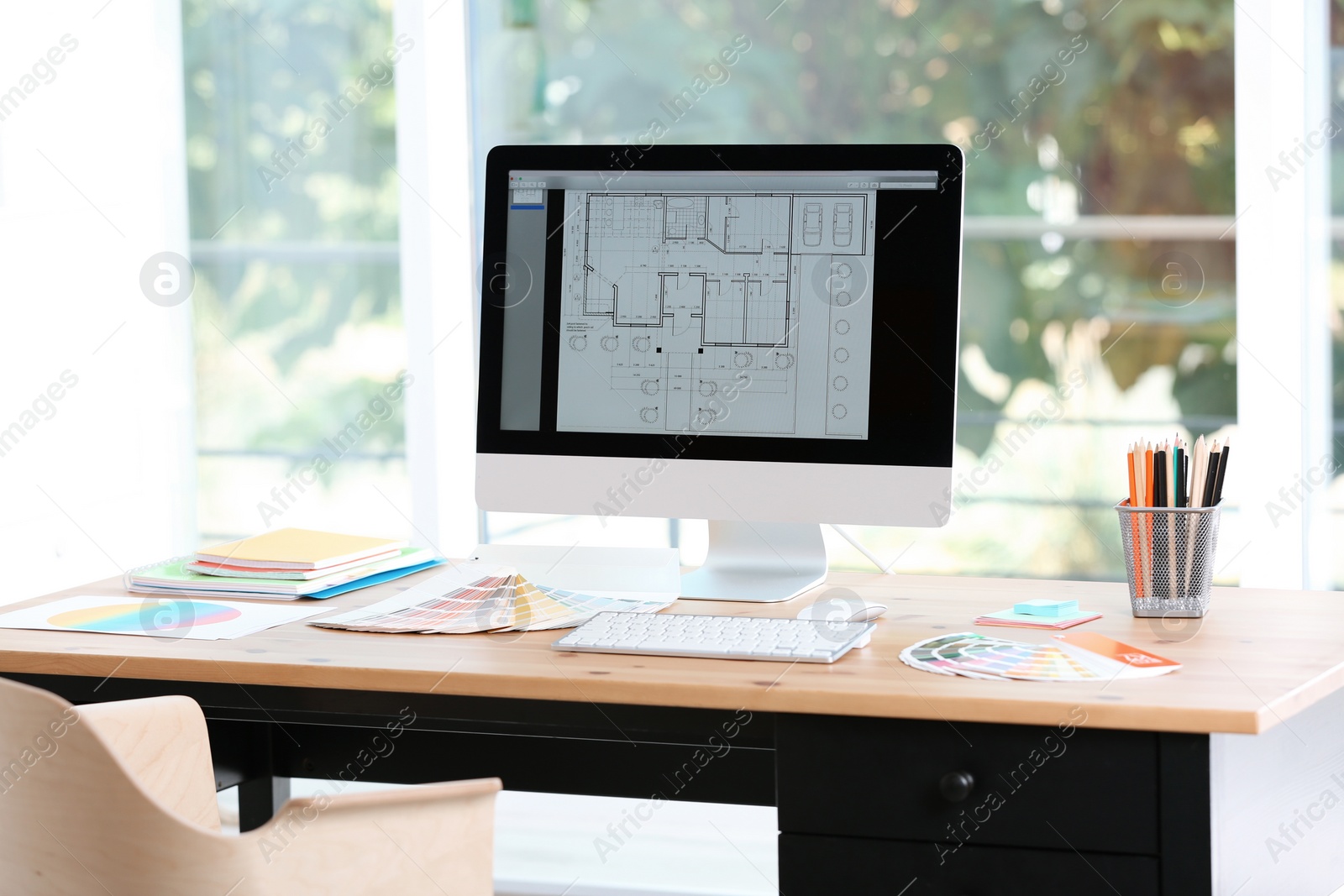 Photo of Designer's workplace with computer and paint color palette samples on table